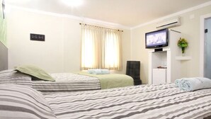 A hotel room with two beds, a television, a small desk, and a window with curtains. - Monte Serrat Hotel (Santos)