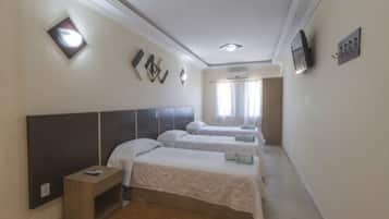 Habitación de hotel con dos camas, una mesita de noche, televisión y ventana con cortinas.