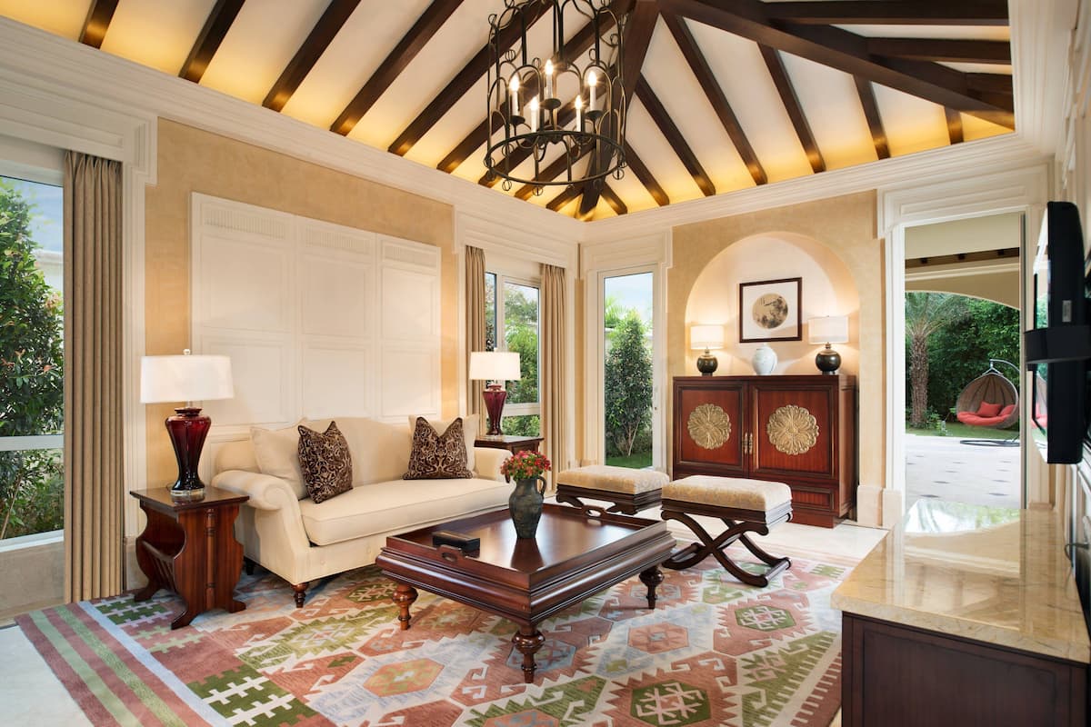 A spacious living room with a high ceiling, a large window, and a view of the outdoors.