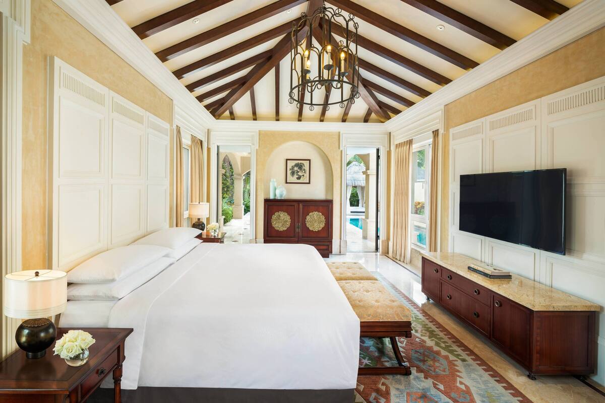 A spacious bedroom with a large bed, a TV, and a wooden cabinet.