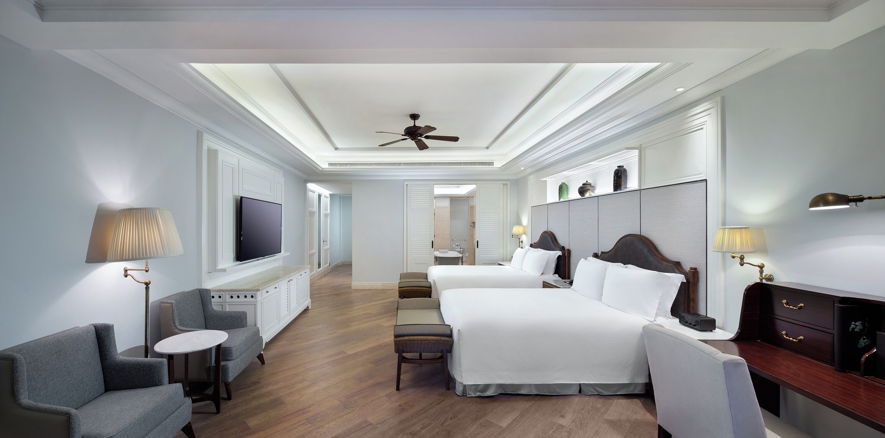 Habitación de hotel con dos camas, televisión, escritorio y una silla.