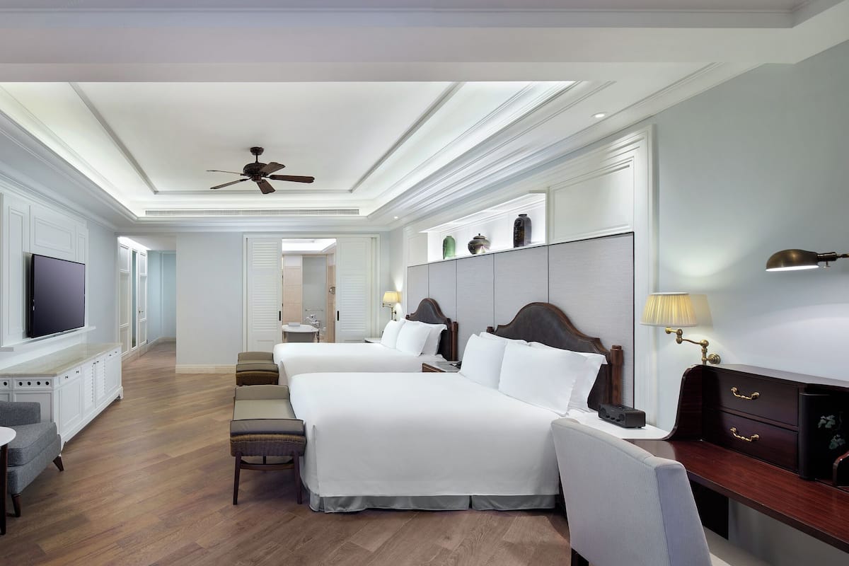 A hotel room with two beds, a TV, a desk, and a chair.