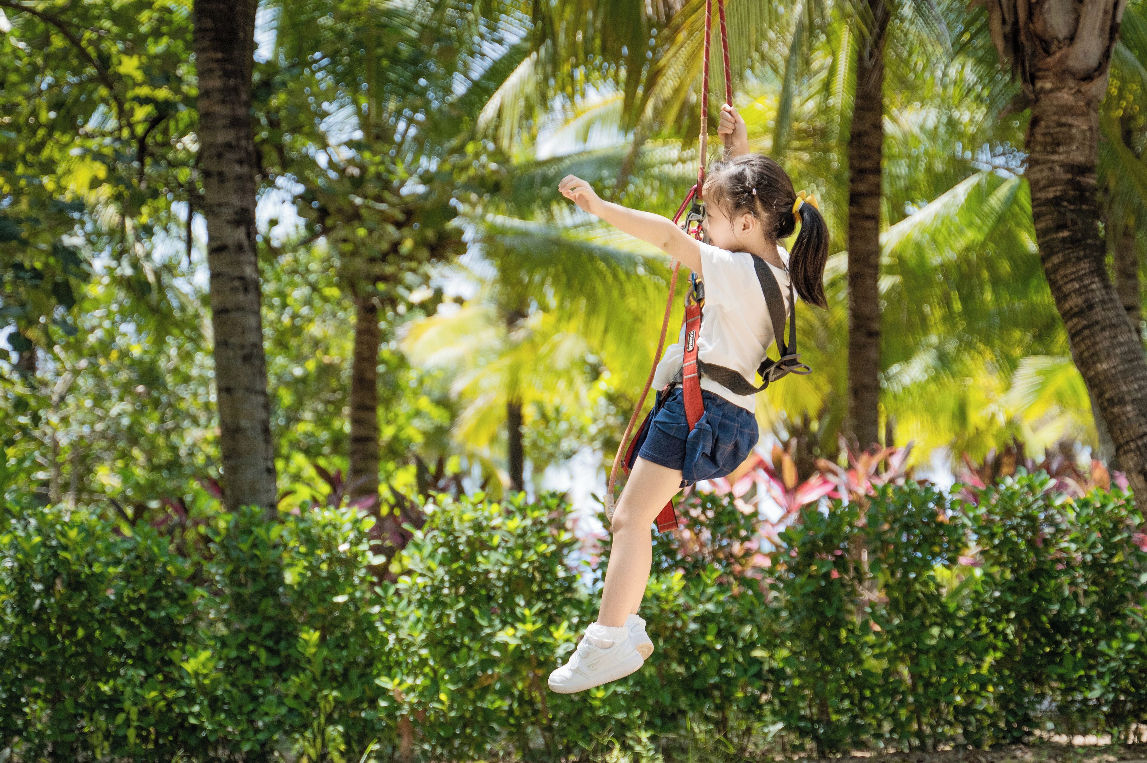 A person on a swing in a lush, green outdoor setting.