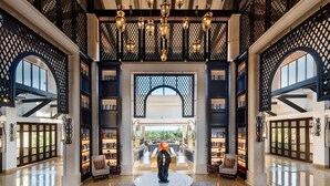 A spacious lobby with a central round table, bookshelves, and a large arched window.