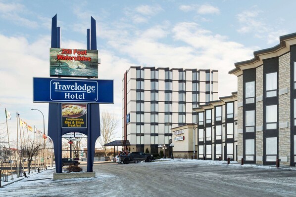 A Travelodge Hotel with a sign advertising 250 foot waterslides, complimentary breakfast, and seafood delivery.