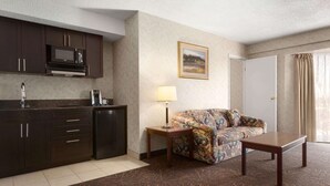 Een hotelkamer met een kitchenette, een bank, een salontafel en een lamp.