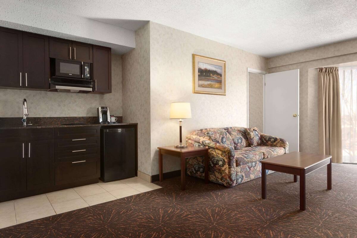 Een hotelkamer met een kitchenette, een bank, een salontafel en een lamp.