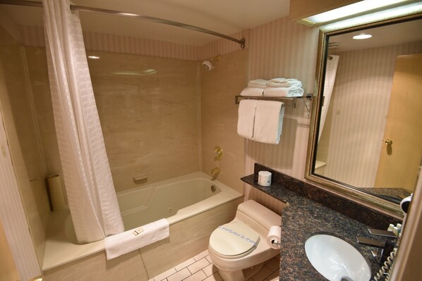 A bathroom with a bathtub, toilet, sink, and a mirror.