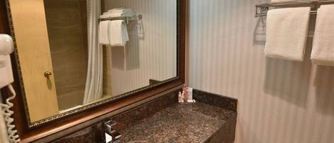 A bathroom with a marble sink, a large mirror, a towel rack, and a toilet.