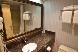 A bathroom with a marble sink, a large mirror, a towel rack, and a toilet.