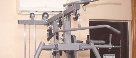 A gym with exercise equipment, a door with a sign, and an air conditioning unit on the wall.