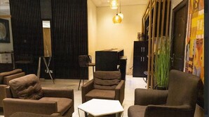 A modern living room with brown sofas, a white coffee table, and a television. - Airport West Hotel (Accra)