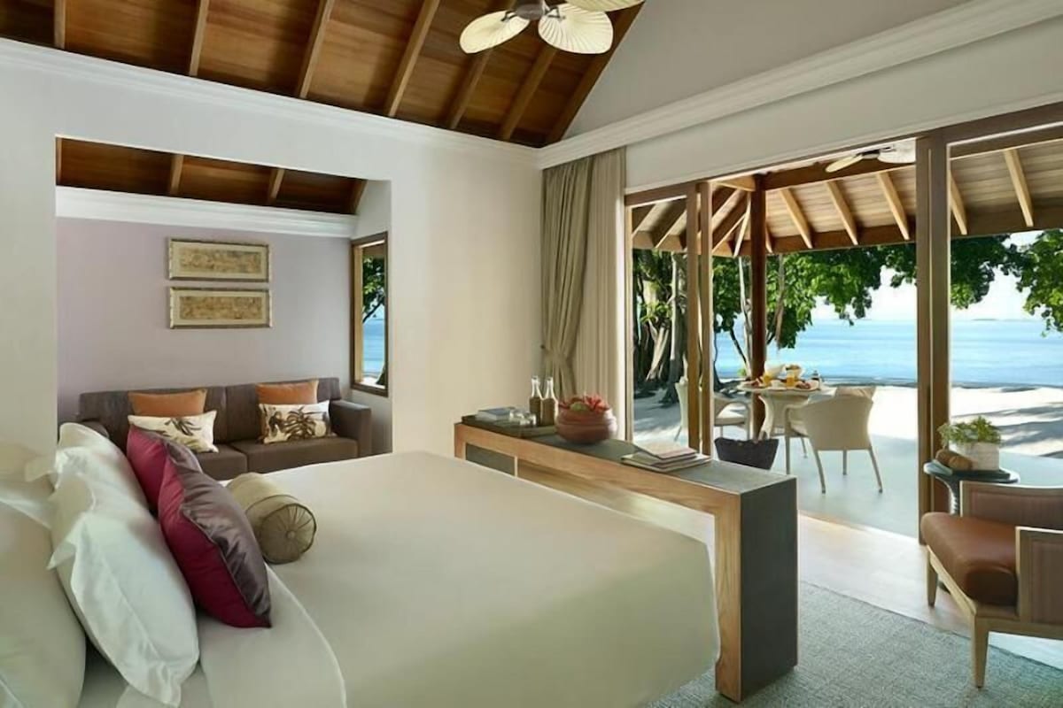Un dormitorio con cama, escritorio y vista a la playa.