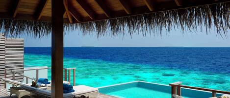 A wooden deck with a pool, lounge chairs, and a table with fruit.