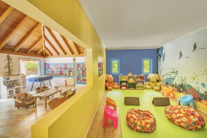 A children's playroom with a wooden ceiling, colorful furniture, and a mural.