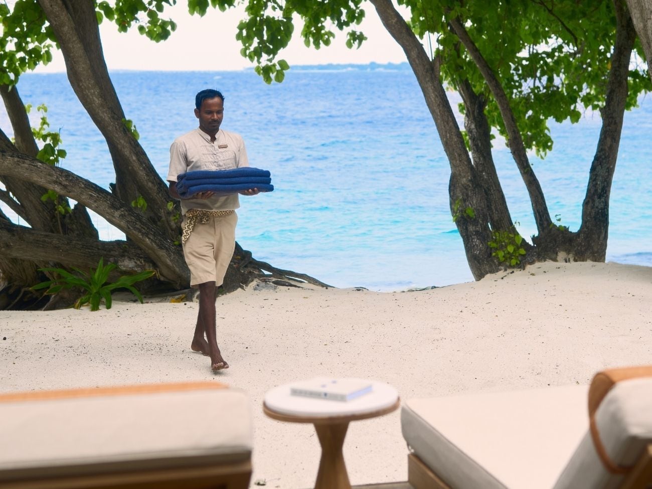 Une scène de plage avec une personne portant des serviettes bleues, une plage de sable et une vue sur la mer.