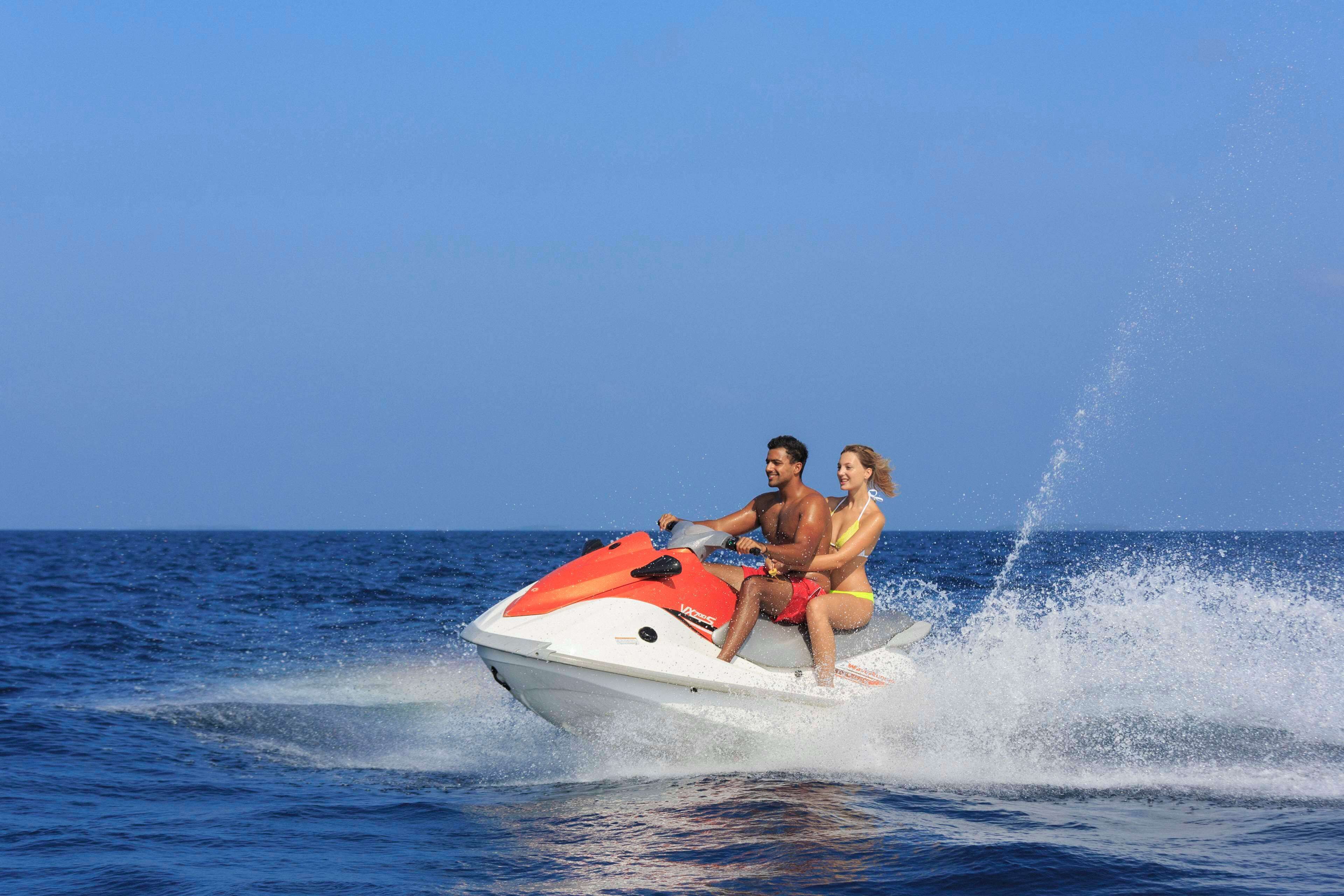 A jet ski with two people on it, moving through the water.