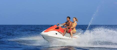 A jet ski with two people on it, moving through the water.