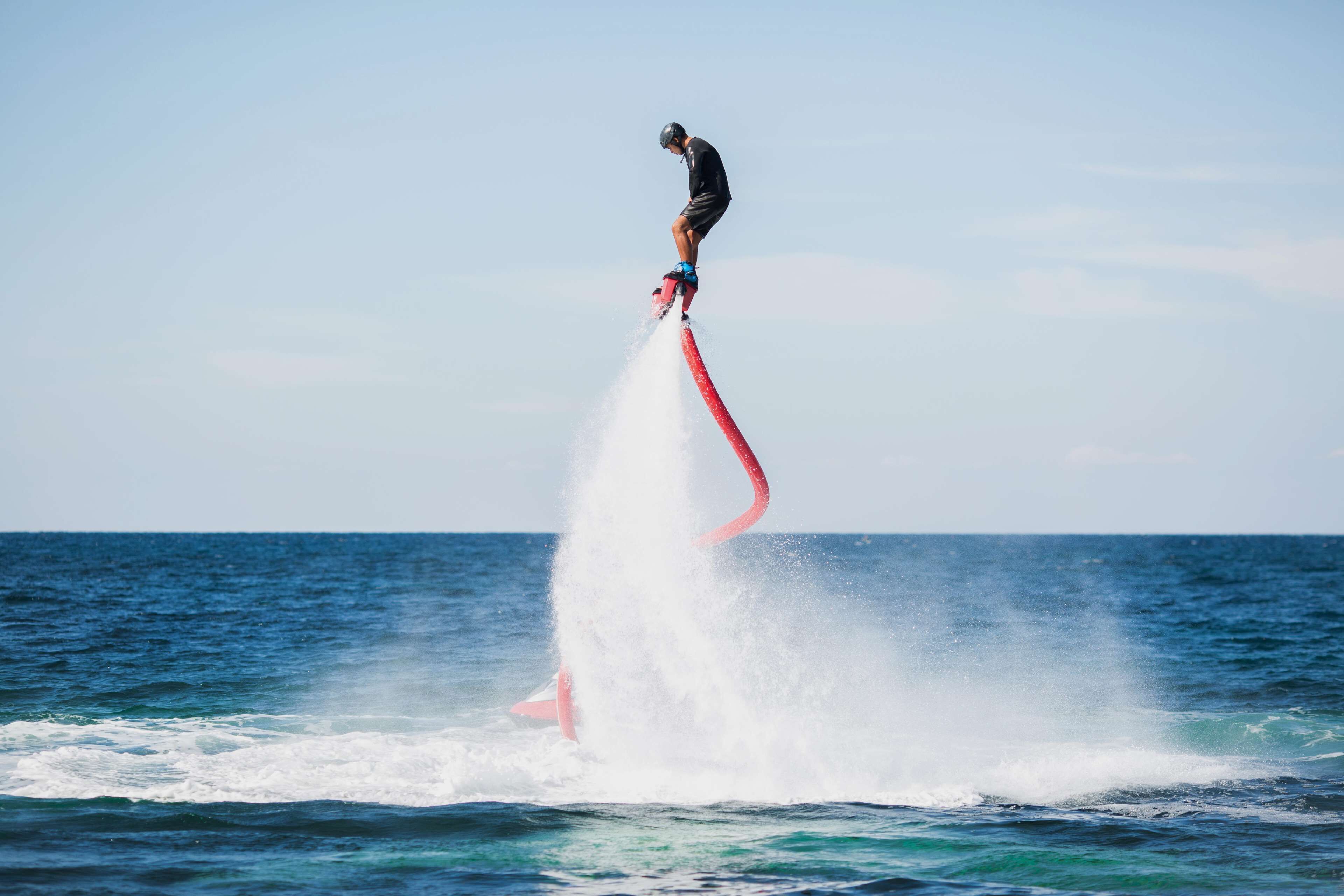 Una persona surfeando una ola con una tabla roja.