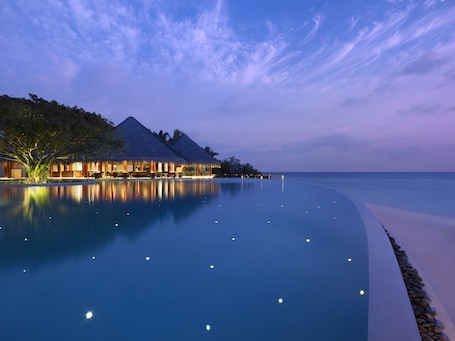 A resort with overwater bungalows, a infinity pool, and a beach view.