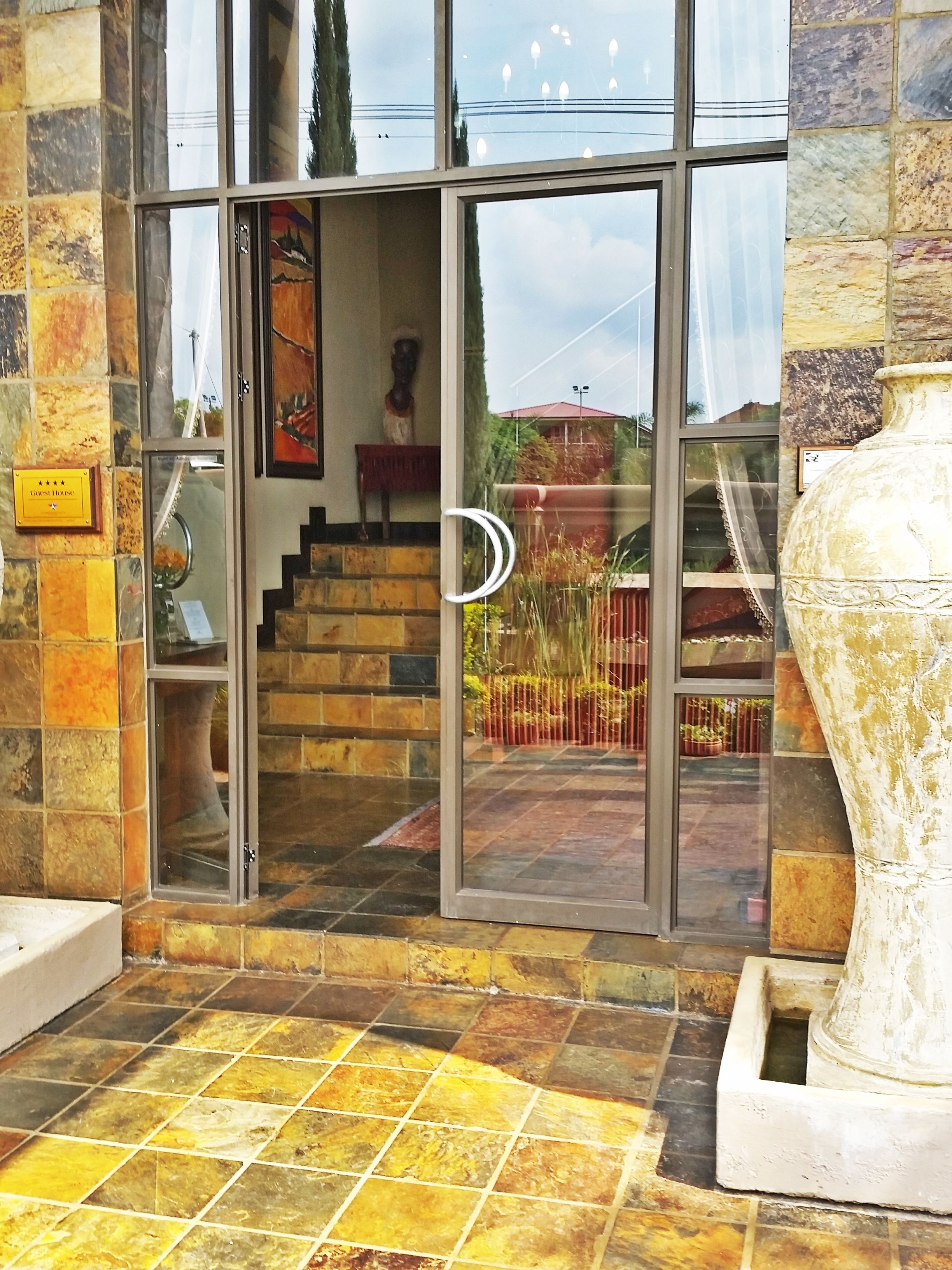 Entrada de un hotel con fachada de piedra, puerta de cristal y una escalera que conduce al interior.