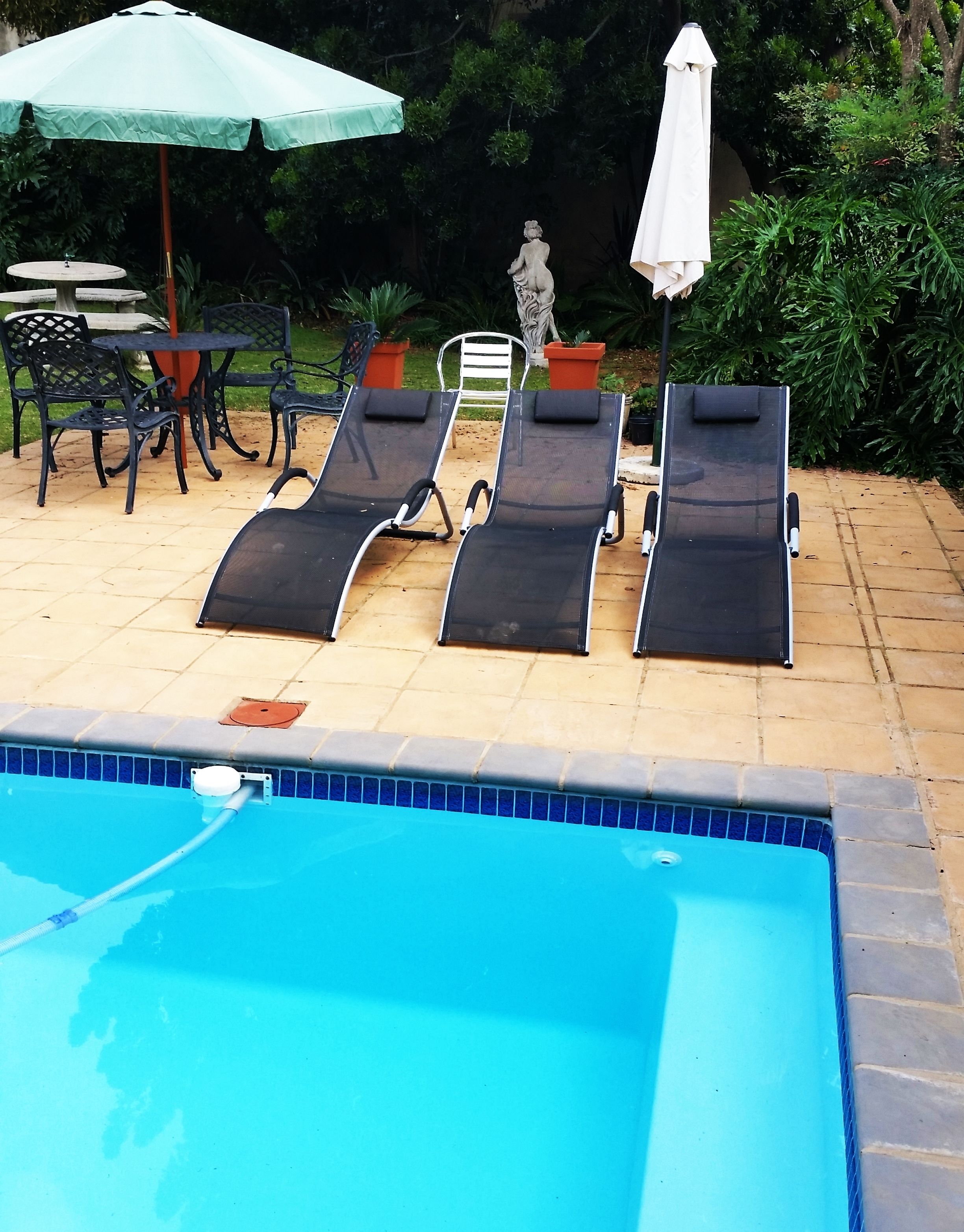 Una piscina al aire libre, sillones reclinables de piscina