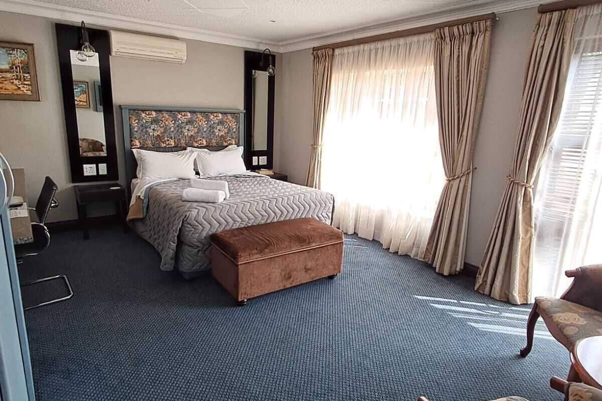 Une chambre d’hôtel avec un grand lit, un petit canapé, un bureau et une chaise.