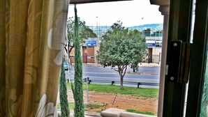 A window view of a courtyard with a small water feature, a paved area, and a tree.