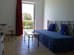 Un dormitorio con cama, una mesita y ventana con vistas a zonas verdes.