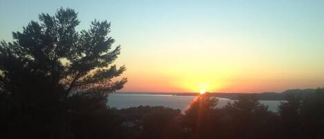 A sunset over a body of water with trees in the foreground.