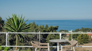 A balcony with wicker chairs and a table overlooking a coastal view. - Liberatos Village (Kefalonia)