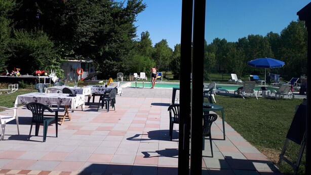 An outdoor patio with tables and chairs, a pool, and a grassy area. - Ecogarden (Mestre)