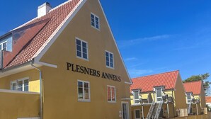 A yellow building with the name "Plesners Anneks" on the facade, featuring multiple windows and a red-tiled roof. - Plesners Anneks (Skagen)