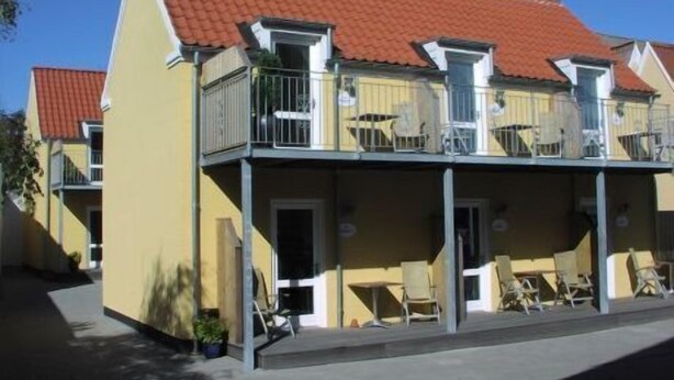 A two-story building with a red-tiled roof, balconies with metal railings, and a flat facade. - Plesners Anneks (Skagen)