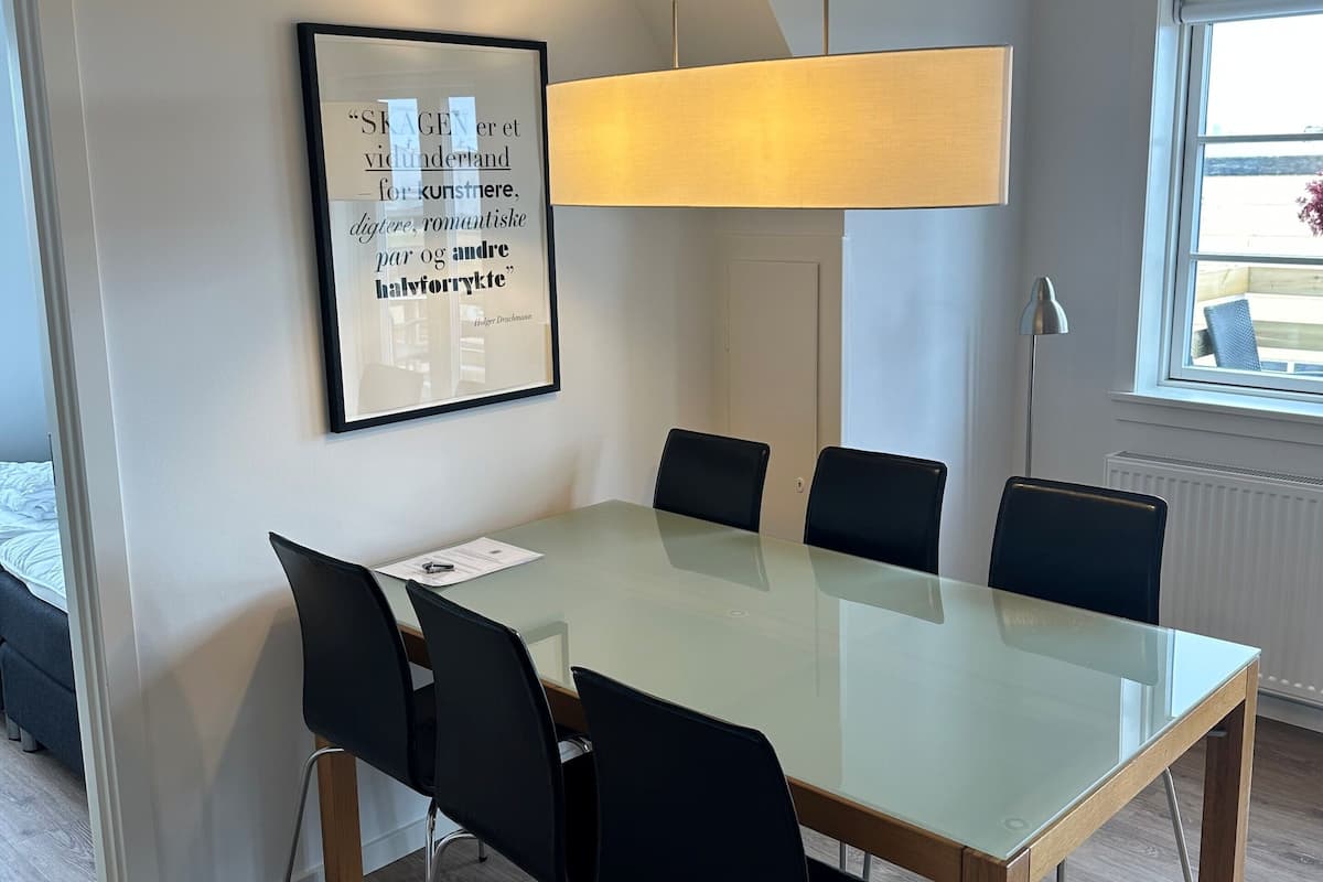 Une salle de réunion moderne avec une table en verre, des chaises noires, une citation encadrée au mur et un grand luminaire suspendu.