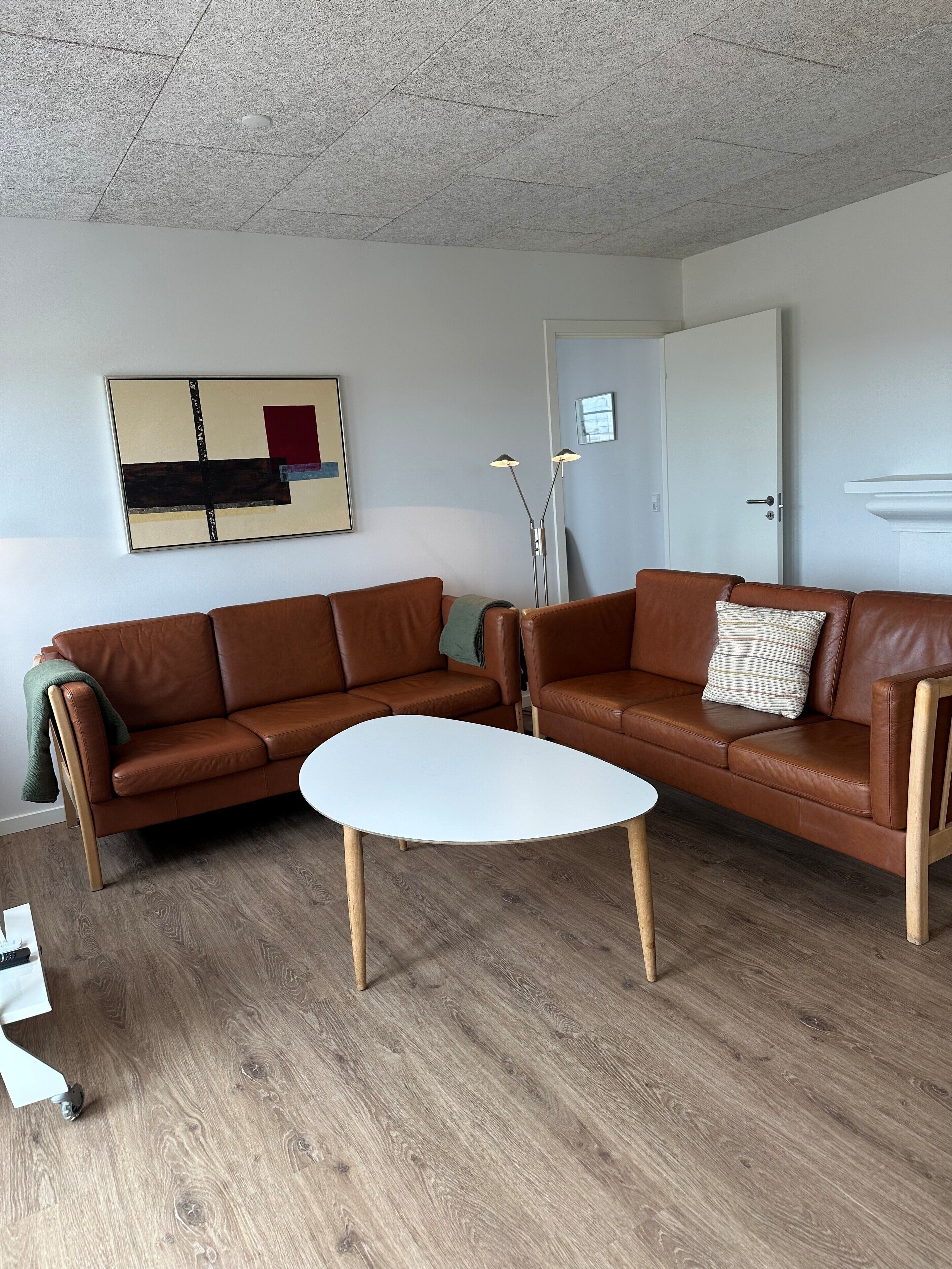 A modern living room with a brown leather sofa, a white coffee table, and a wooden floor.