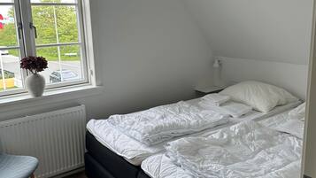 A bedroom with a bed, a radiator, a window, and a chair.