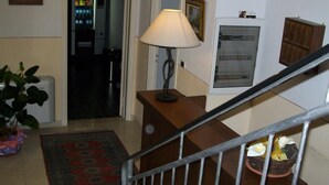 A staircase with a metal railing, a wooden desk with a lamp, a patterned rug, and a basket with flowers. - Bed & Breakfast Locanda La Rotonda (Montale)