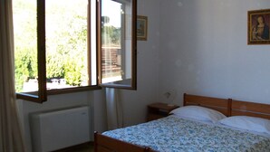 A bedroom with a bed, a nightstand, a window, and a radiator. - Bed & Breakfast Locanda La Rotonda (Montale)