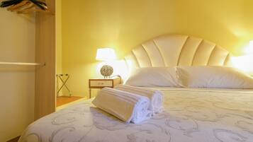 Une chambre d’hôtel avec un lit, une table de chevet, une lampe et une serviette posée sur le lit.