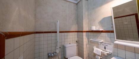 A small, compact bathroom with a toilet, sink, and shower. A sign indicates the flush direction.