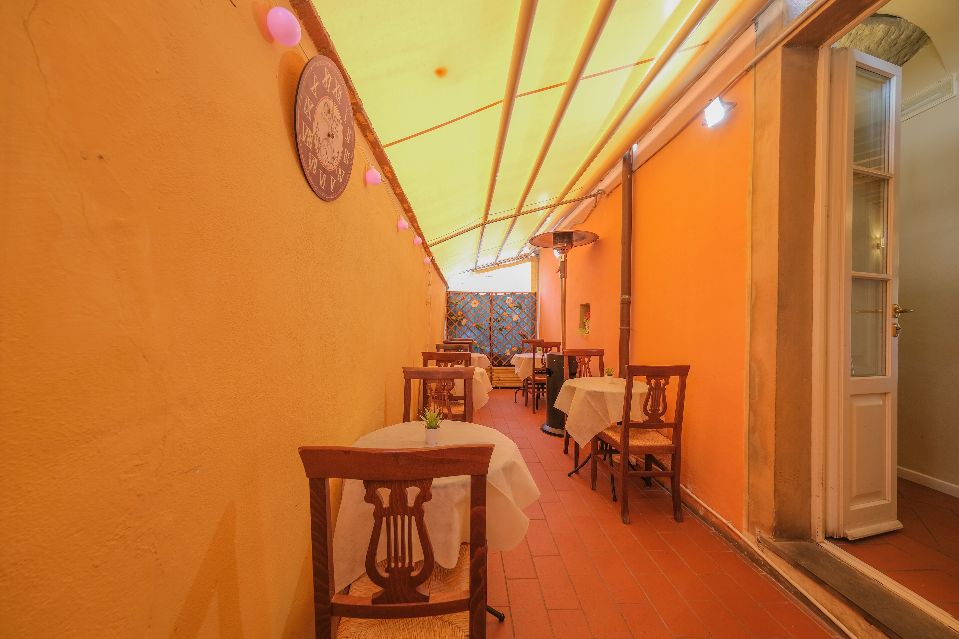 A narrow corridor with tables and chairs, leading to a door.