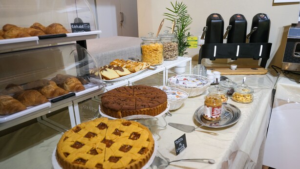 Een buffet met diverse gebakjes, taarten en een koffieapparaat.