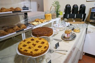 Un bufé con diversos pasteles, tartas y una cafetera.