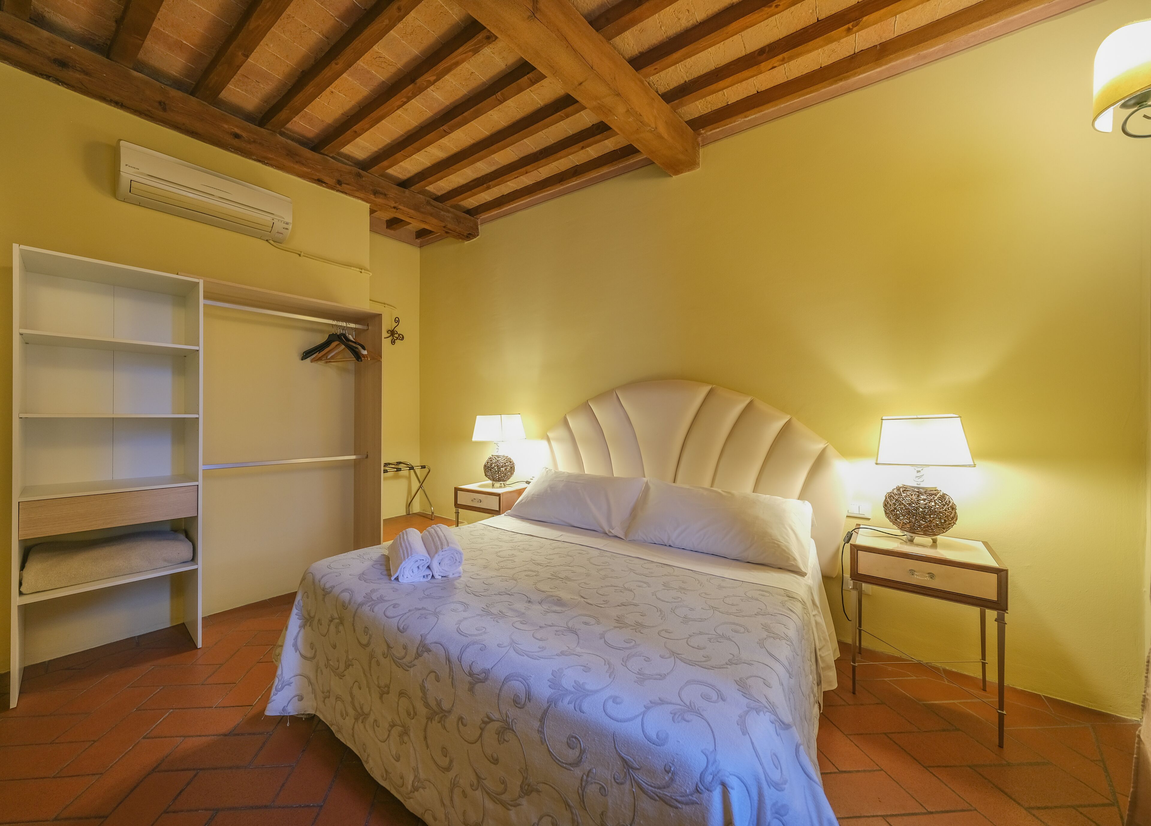 Un dormitorio con una cama, un armario, dos mesitas de noche con lámparas y un ventilador de techo.