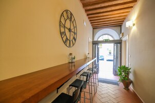 Un pasillo con un banco de madera, un reloj de pared grande y una planta en maceta.