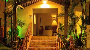 Una escalera que lleva a una habitación con una cama, una silla y una planta en maceta.