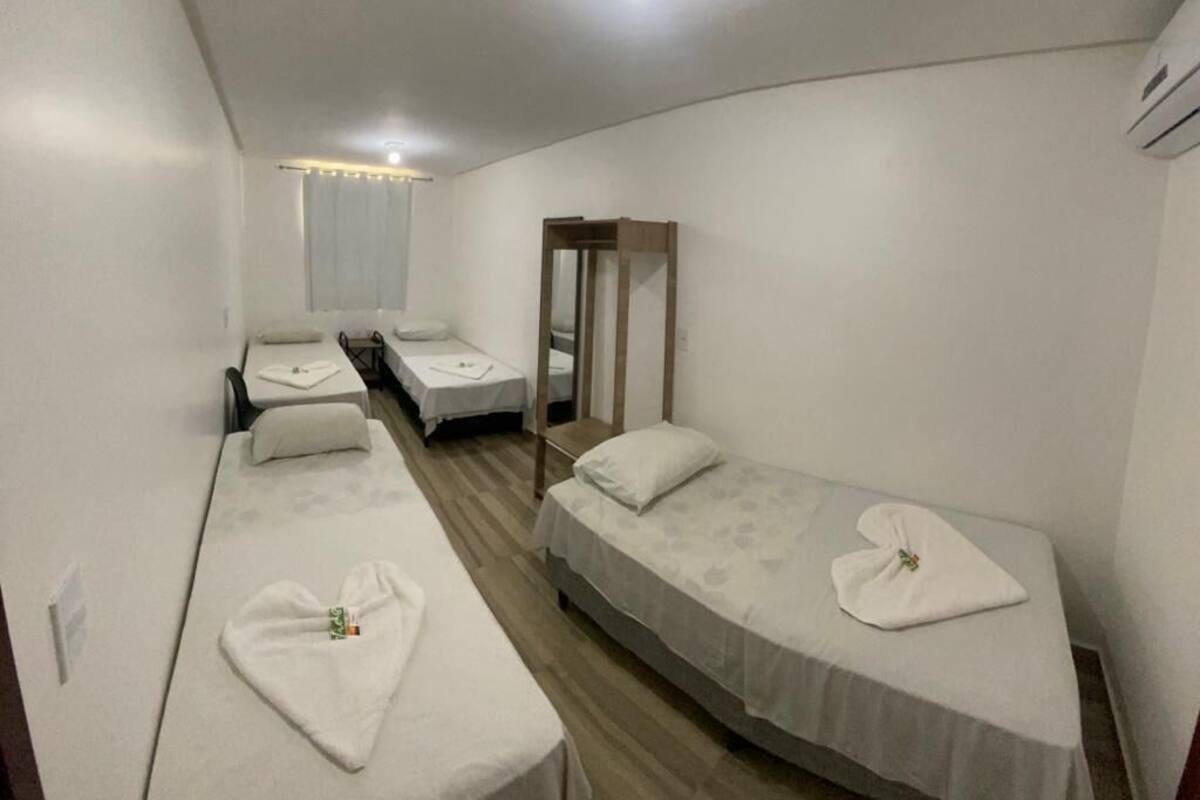 Habitación de hotel compacta con dos camas individuales, una mesita, un espejo y una lámpara en el techo.