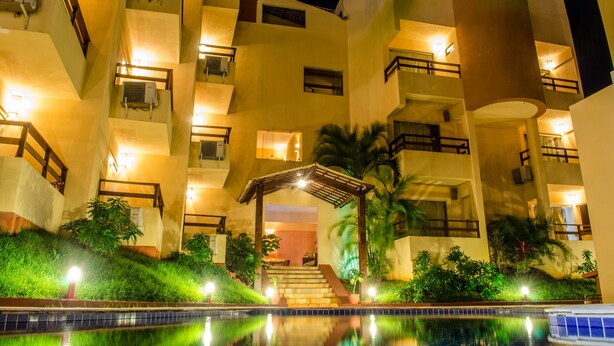 Un hotel de varios pisos con balcones, piscina y una entrada cubierta.