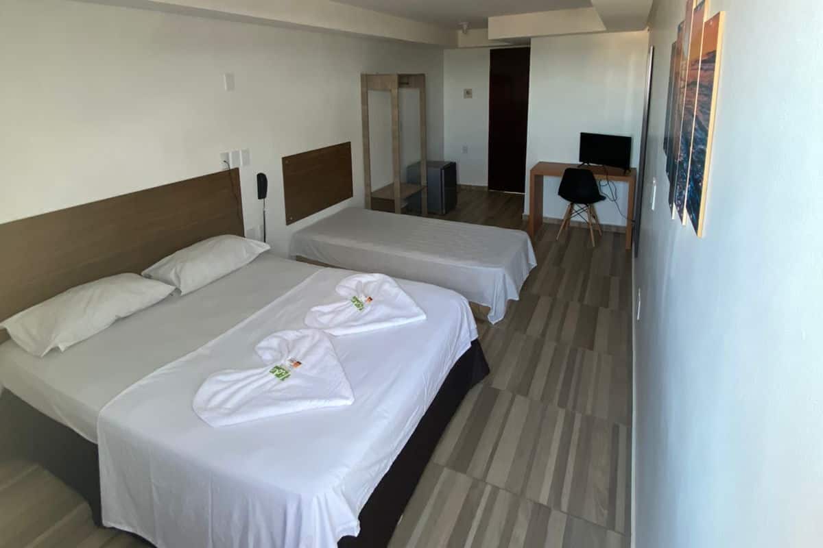 Habitación de hotel con dos camas, un escritorio y una silla.